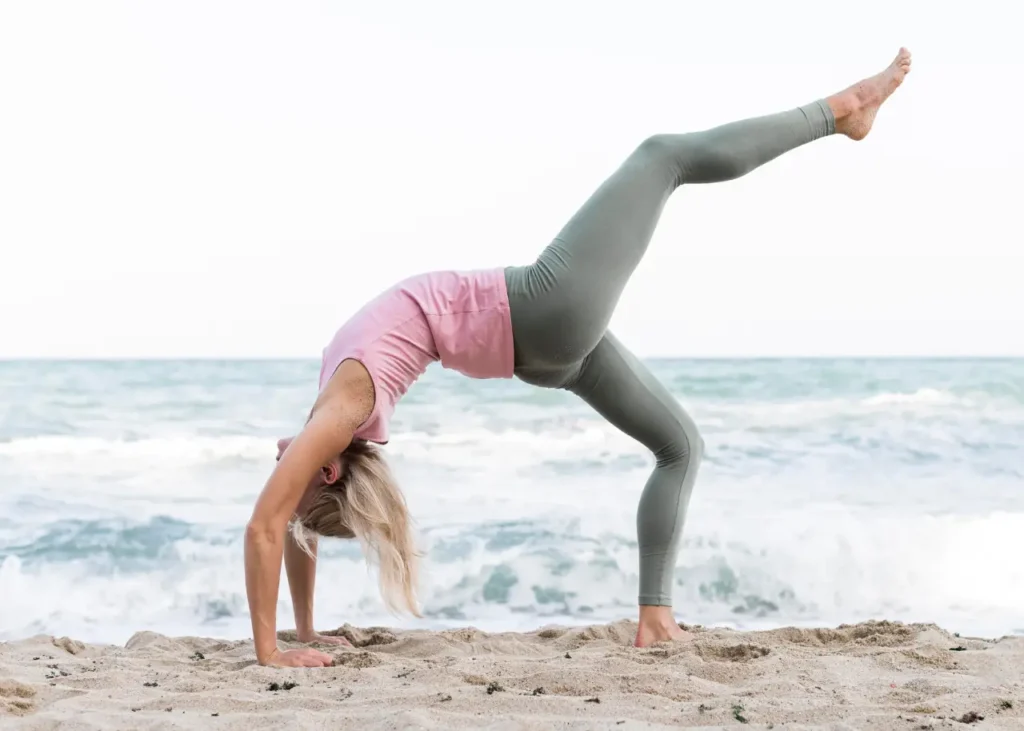 Mujer bella practicando yoga en la playa