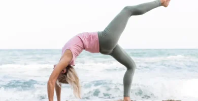 Mujer bella practicando yoga en la playa