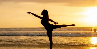 Mujer practicando posturas de yoga de pie frente al mar