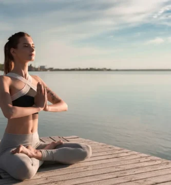 Mujer practicando yoga junto al mar