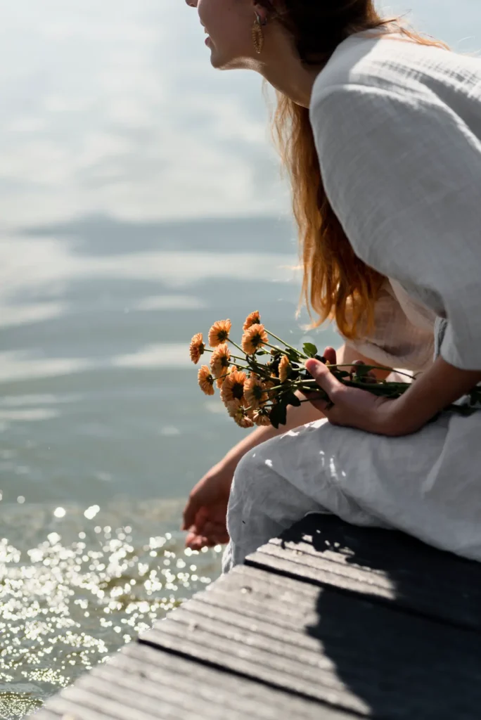 Mujer feliz sentada en un muelle empezando meditación.